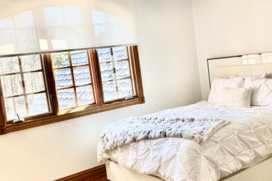 広いモダンスタイルのおしゃれな客用寝室 (白い壁、無垢フローリング、暖炉なし、茶色い床、格子天井)