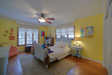 Diseño de dormitorio minimalista de tamaño medio con paredes amarillas, suelo de madera en tonos medios y suelo marrón