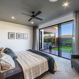 This is an example of an expansive contemporary master bedroom in Brisbane with white walls, carpet and grey floor.