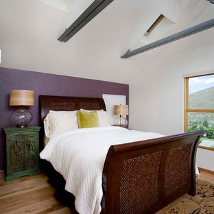 Imagen de dormitorio tipo loft, tradicional renovado, grande, con paredes blancas, suelo de madera clara, chimenea tradicional, marco de chimenea de yeso y suelo marrón