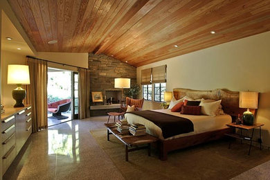 サンタバーバラにある広いコンテンポラリースタイルのおしゃれな主寝室 (ベージュの壁、ラミネートの床、標準型暖炉、石材の暖炉まわり、茶色い床)