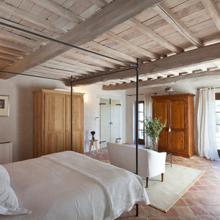 Ejemplo de dormitorio mediterráneo con paredes beige, suelo de baldosas de terracota y suelo rojo