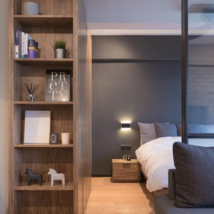 This is an example of a small industrial master bedroom in Hong Kong with grey walls and plywood floors.