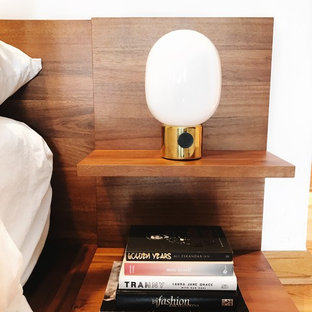 Modelo de dormitorio principal, minimalista, extra grande, con paredes blancas, suelo laminado, chimenea tradicional, marco de chimenea de baldosas y/o azulejos y suelo marrón