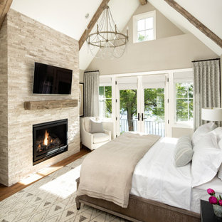 Mittelgroßes Klassisches Hauptschlafzimmer mit beiger Wandfarbe, braunem Holzboden, Kamin, Kaminumrandung aus Stein und braunem Boden in Minneapolis