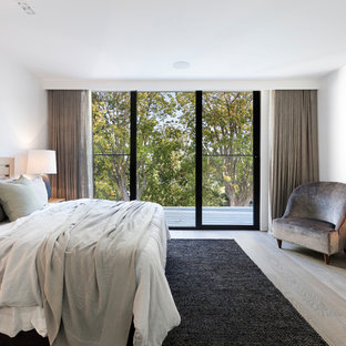 This is an example of a contemporary master bedroom in Melbourne with white walls, light hardwood floors and beige floor.