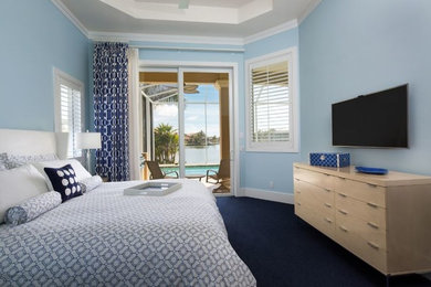 Modelo de dormitorio costero de tamaño medio sin chimenea con paredes azules, moqueta y suelo beige