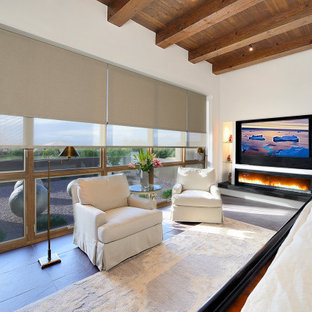 Imagen de dormitorio principal, de estilo americano, grande, con paredes blancas, suelo de pizarra, chimenea lineal, marco de chimenea de yeso y suelo marrón
