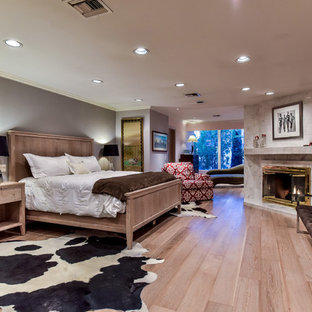 Foto de dormitorio principal, retro, grande, con paredes grises, suelo de madera clara, chimenea de esquina, marco de chimenea de baldosas y/o azulejos y suelo beige