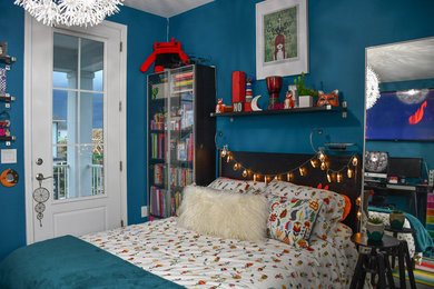 Modelo de habitación de invitados bohemia de tamaño medio con paredes azules, suelo de madera oscura y suelo gris
