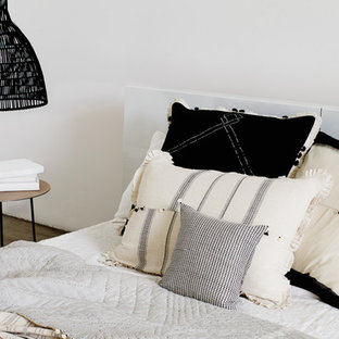Imagen de dormitorio tipo loft, minimalista, grande, con paredes blancas, suelo de cemento, chimenea tradicional y marco de chimenea de yeso
