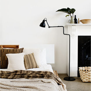 Ejemplo de dormitorio tipo loft, minimalista, grande, con paredes blancas, suelo de cemento, chimenea tradicional y marco de chimenea de madera