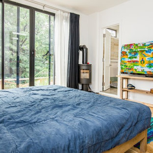 Imagen de dormitorio principal, marinero, grande, con paredes blancas, suelo de madera clara y estufa de leña