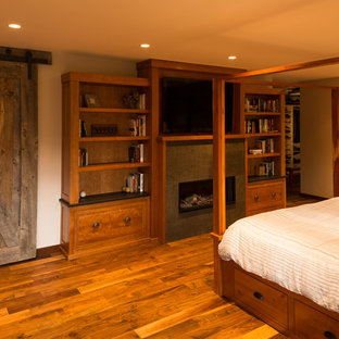 Imagen de dormitorio principal, rural, de tamaño medio, con paredes beige, suelo de madera en tonos medios, chimenea lineal y marco de chimenea de baldosas y/o azulejos