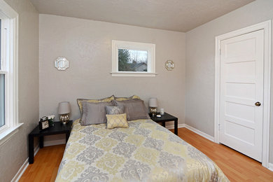 Cette photo montre une chambre parentale craftsman de taille moyenne avec un mur gris et un sol en bois brun.
