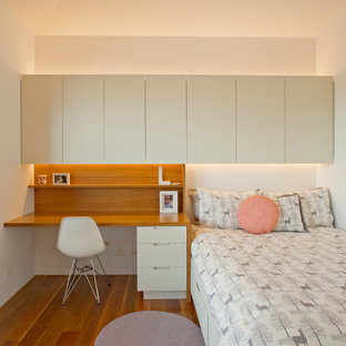 Foto di una camera da letto design con pareti bianche, pavimento in legno massello medio e angolo studio