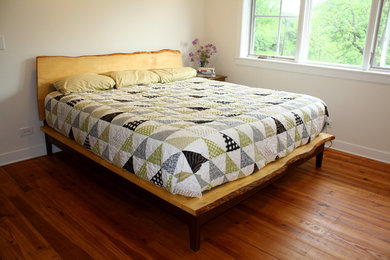 Example of a mid-sized country guest medium tone wood floor bedroom design in Milwaukee with white walls and no fireplace