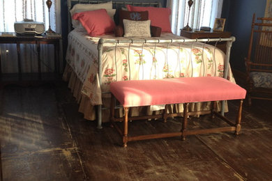 This is an example of a rural bedroom in Dallas with plywood flooring.