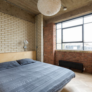 This is an example of an industrial bedroom in London with white walls, light hardwood flooring and beige floors.