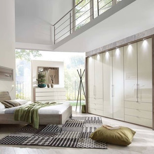 Modelo de dormitorio tipo loft, minimalista, grande, sin chimenea, con paredes blancas, suelo de baldosas de cerámica y suelo beige