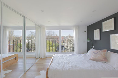 Contemporary master bedroom in London with grey walls and light hardwood flooring.