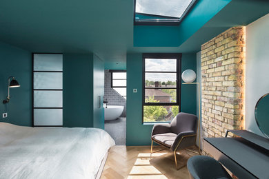 Foto de dormitorio principal contemporáneo sin chimenea con paredes verdes, suelo de madera clara y suelo beige