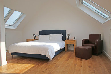 Contemporary master bedroom in Hertfordshire with light hardwood flooring.