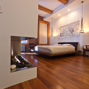 Esempio di una camera da letto design con pareti bianche e pavimento marrone