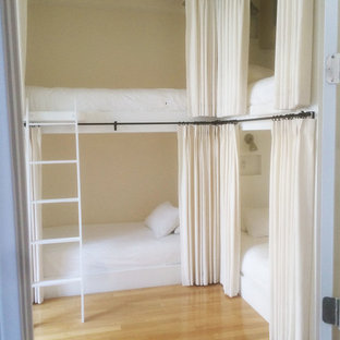 Modelo de dormitorio urbano, pequeño, sin chimenea, con paredes beige y suelo de madera clara