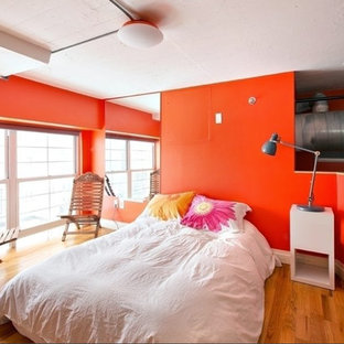Diseño de dormitorio tipo loft, pequeño, con parades naranjas y suelo de madera en tonos medios