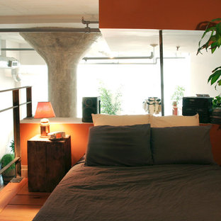 Ejemplo de dormitorio tipo loft, pequeño, con parades naranjas y suelo de madera en tonos medios