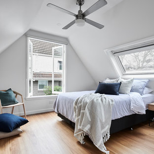 Design ideas for a large contemporary guest bedroom in Sydney with white walls, medium hardwood floors, brown floor and no fireplace.