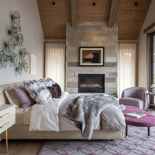 Immagine di una camera matrimoniale stile rurale con pareti bianche, parquet chiaro, camino lineare Ribbon, cornice del camino in pietra e soffitto in legno