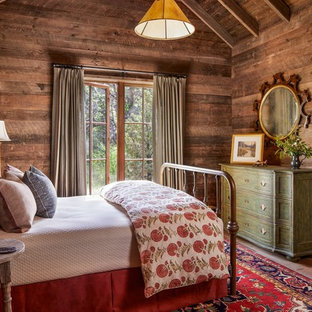 Modelo de dormitorio rural, sin chimenea, con paredes marrones y suelo de madera en tonos medios