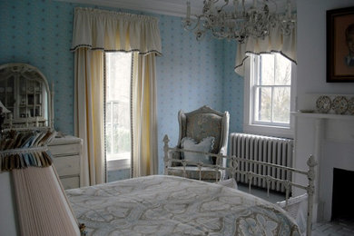 Cette photo montre une petite chambre d'amis chic avec un mur bleu, parquet peint, une cheminée standard et un manteau de cheminée en plâtre.