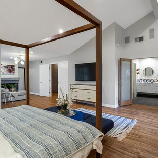 Foto de dormitorio principal, contemporáneo, extra grande, con paredes grises, suelo de madera clara, chimenea tradicional, marco de chimenea de hormigón y suelo gris