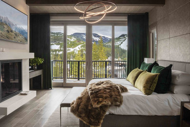 Modelo de dormitorio rústico con paredes grises, suelo de madera en tonos medios, todas las chimeneas y suelo marrón