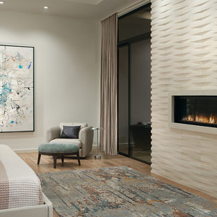 Großes Modernes Hauptschlafzimmer mit weißer Wandfarbe, hellem Holzboden, Gaskamin, Kaminumrandung aus Stein und beigem Boden in Phoenix