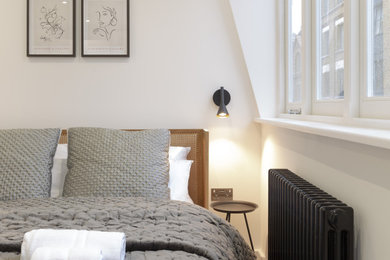 Imagen de dormitorio contemporáneo de tamaño medio con paredes blancas, suelo de madera clara y suelo beige