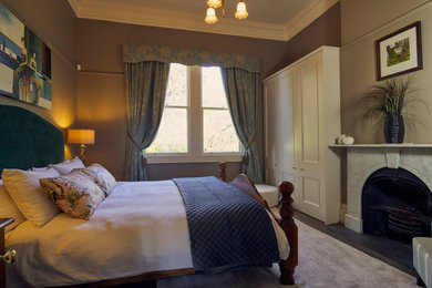 Foto de habitación de invitados abovedada tradicional grande con paredes beige, moqueta, todas las chimeneas, marco de chimenea de madera y suelo beige