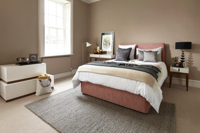 This is an example of an expansive modern master bedroom in Devon with carpet and beige floors.