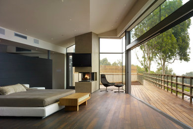 Example of a mid-sized trendy master dark wood floor bedroom design in Los Angeles with beige walls, a stone fireplace and a corner fireplace