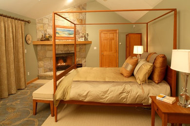 Modelo de dormitorio principal rústico grande con moqueta, chimenea de esquina, marco de chimenea de piedra, suelo beige y paredes verdes