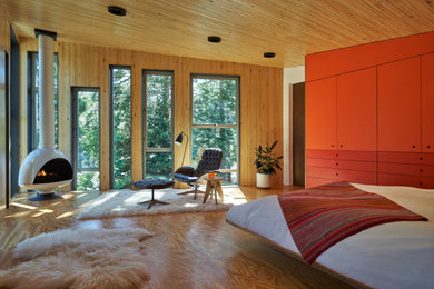 На фото: спальня в современном стиле с коричневыми стенами, паркетным полом среднего тона, печью-буржуйкой, коричневым полом, деревянным потолком и деревянными стенами