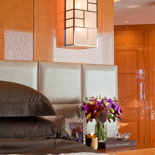 Imagen de dormitorio principal, contemporáneo, de tamaño medio, con parades naranjas, suelo de madera en tonos medios, chimenea lineal y marco de chimenea de metal