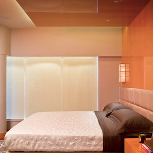 Imagen de dormitorio principal, contemporáneo, de tamaño medio, con parades naranjas, suelo de madera en tonos medios, chimenea lineal y marco de chimenea de metal