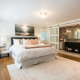 Ispirazione per una grande camera matrimoniale boho chic con pareti grigie, parquet scuro, camino sospeso, cornice del camino piastrellata e pavimento marrone
