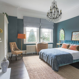 This is an example of a classic master bedroom in Kent with blue walls, dark hardwood flooring and a standard fireplace.