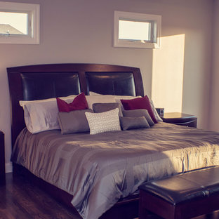 Imagen de dormitorio principal, moderno, grande, con paredes beige, suelo de madera oscura, chimenea tradicional y marco de chimenea de baldosas y/o azulejos