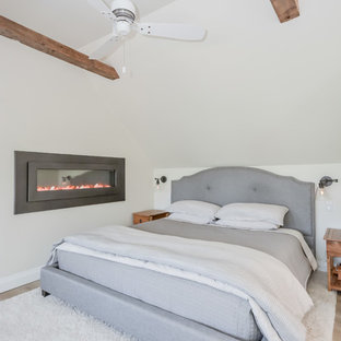 Foto de dormitorio tipo loft, de estilo de casa de campo, con paredes beige, suelo de baldosas de cerámica, chimenea lineal y suelo gris